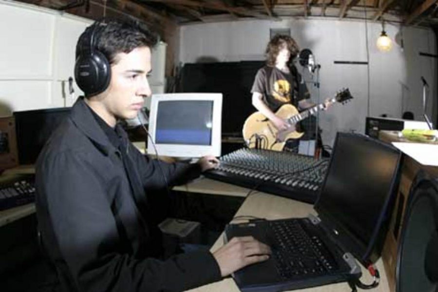 Former MC student Jonathan Avila, foreground, works with musicians and bands at his recording studio, Insomnyac Entertainment, in Oxnard.  The fledgling company helps support local artists like Brandon Boutell, background, a member of local band the Whirled Peas.