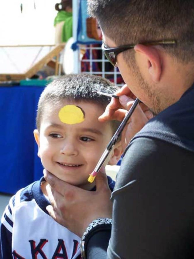 Students, faculty and staff enjoyed Multicultural Day. VC representative for EOPS Hector Perez, 18, attempts to paint a Batman logo on top of 3-year-old Tony Alfaro's forehead.