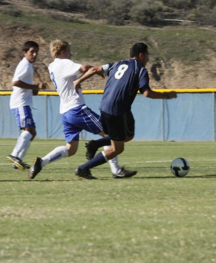 A Raiders player attempts to break away from Condor midfielder Sam Nellis in a WSC match-up Tuesday afternoon. The Raiders tied the Condors 1-1.
