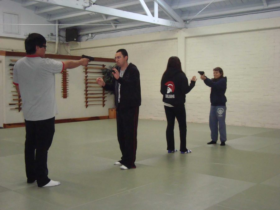 Students in Larry Reynosas self-defense/assault prevention class take turns filling in as victims and potential attackers in a handgun disarming exercise.