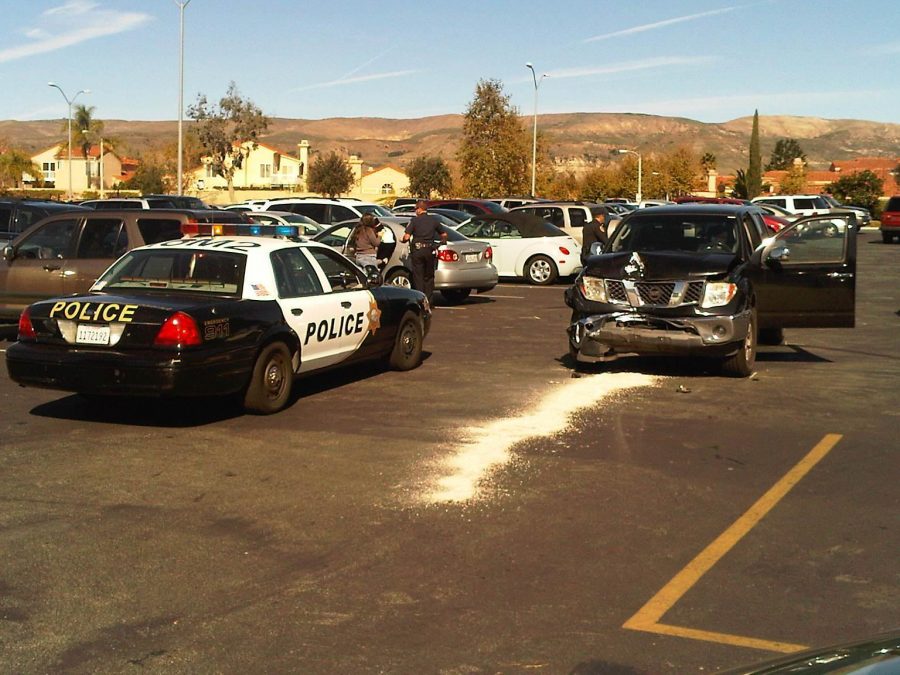 Campus police assess the damage sustained by a Nissan Frontier after a parking lot accident at an unusually high speed.