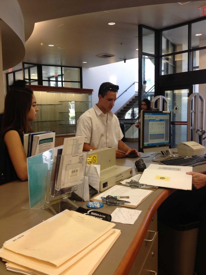 Isaiah Wallot and Alma Zepeda checking out books at the Moorpark College library circulation desk.