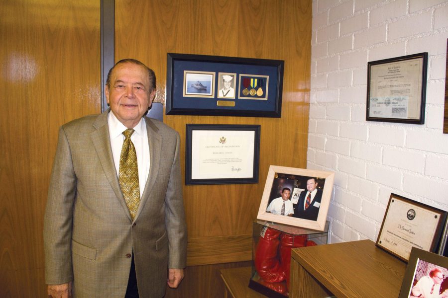 Moorpark College President Bernard Luskin stands next to his memorabilia wall located in his office. Of the various items of interest, pictured are medals from his days in the Navy and a photo with boxer Muhammad Ali along with his boxing gloves.