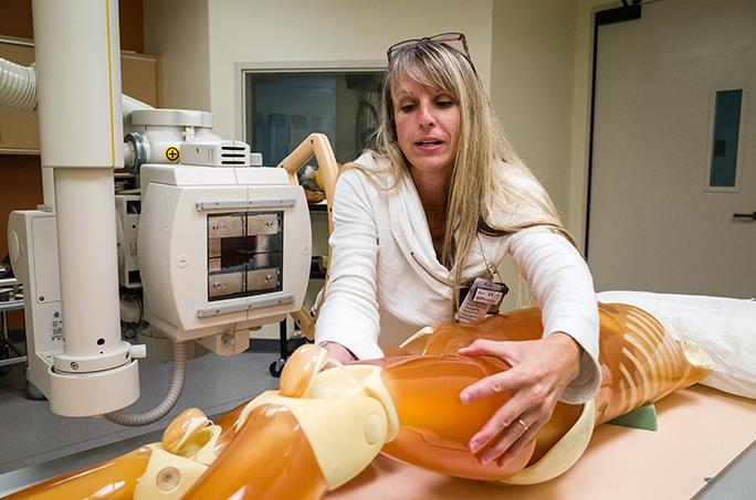 Radiology Technologist Ashley Read, 44, positions a dummy phantom patient for a mock x-ray in the Analog Lab on campus Oct. 14.