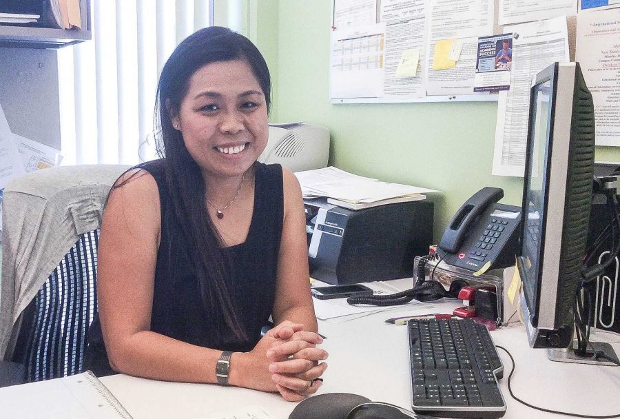 Stacey Chen smiles into the camera while in her office, welcoming international students.