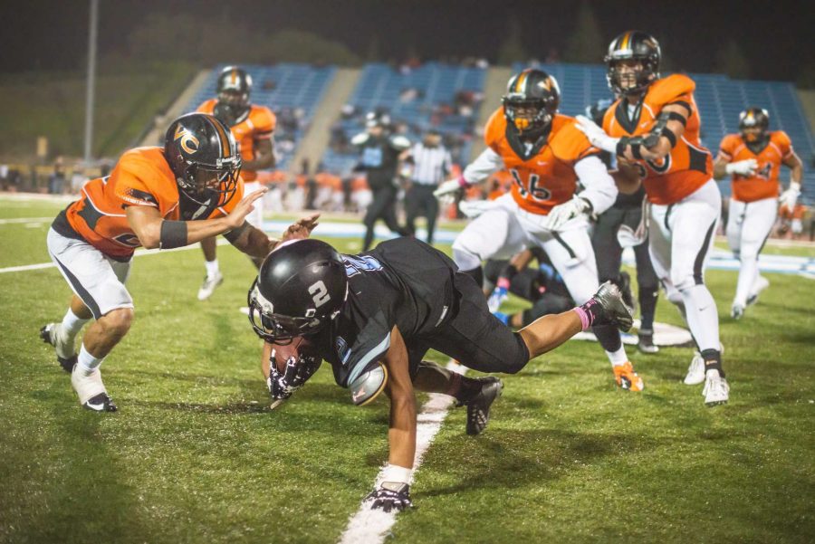 Derrick Reynolds, who usually plays as a defensive back, falls while still managing to hang onto the ball during a rivalry game with Ventura. Photo credit: James Schaap