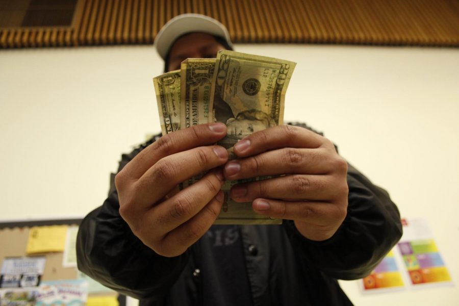 Miguel Arana, a 19-year-old psychology major, holds up some cash. Photo credit: Merleen Ruiz