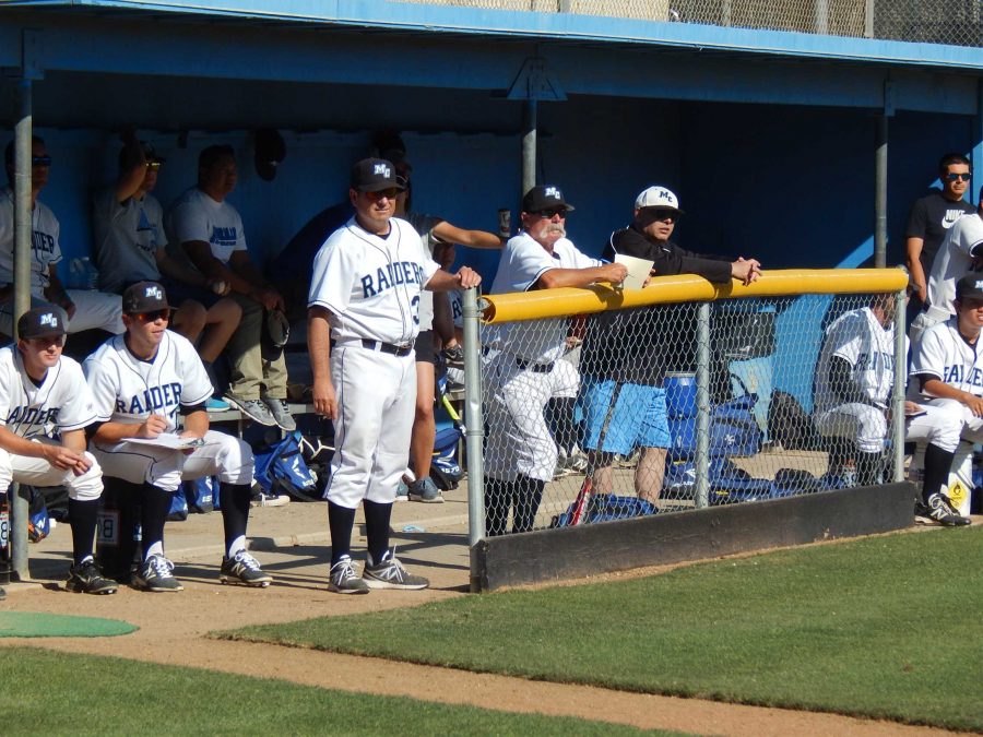 Pitching Coach Curtis Scott stands next to Head Coach Mario Porto in the Moorpark dugout in the game against the Pierce College Brahmas on Tuesday. The Raiders won 5-3.