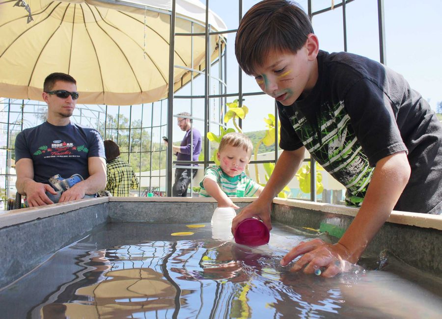 Mark Aten watches over Parker Aten, 2, and Jimmy Cobb, 9, as they play with orbies in the water during Discovery Day on Saturday, April 2. Photo credit: Nikolas Samuels