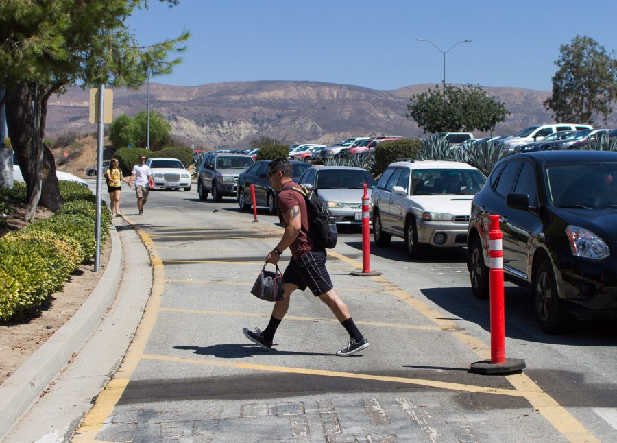 Eloy Baca, a 31-year-old kinesiology major, walks through stopped cars on his way to Moorpark College on Aug. 18. Parking proved to be a challenge for students arriving during peak hours. Photo credit: Willem Schep