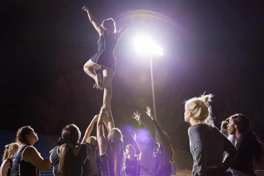 Kenna Potter, 18, is held up by her fellow cheerleaders before being vaulted into the air during evening practice in the Raider Stadium. The cheerleading program has just been brought back this semester after ten years.