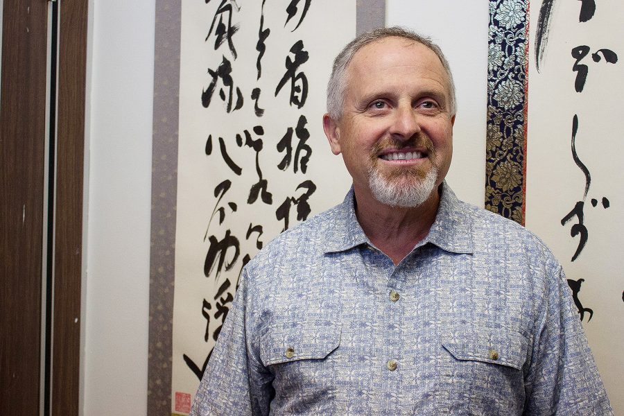 Professor Chad Basile stands in front of two of the scrolls called kakejiku that his master painted for him. Each expresses a specific Bujinkan mantra. Bujinkan is a martial art that Basile teaches on campus. Photo credit: Martin Bilbao