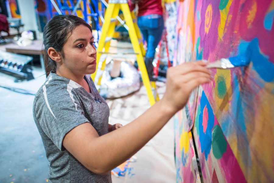 Nancy Trujillo, nursing major, paints her contribution to the set of "HAIR." Photo credit: James Schaap