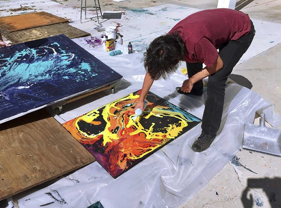 Oscar Rios, an art major and president of the MC Art Club, works on what will eventually become his painting of a monster breaking through the subconscious. Photo credit: Bailey Walters