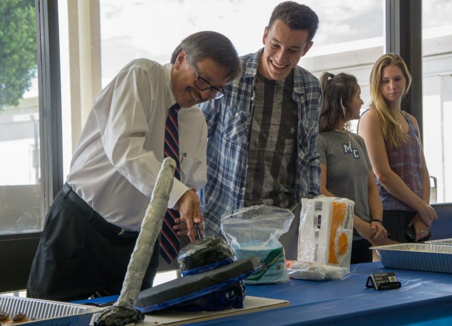 College President Luis Sanchez, left, cuts a Raider-shaped cake with AS President Payton Robinson, 19, Communications major. The cake was one of many anniversary activities that included a writing wall and a presentation by History Professor Patty Colman. Photo credit: Cole Carlson