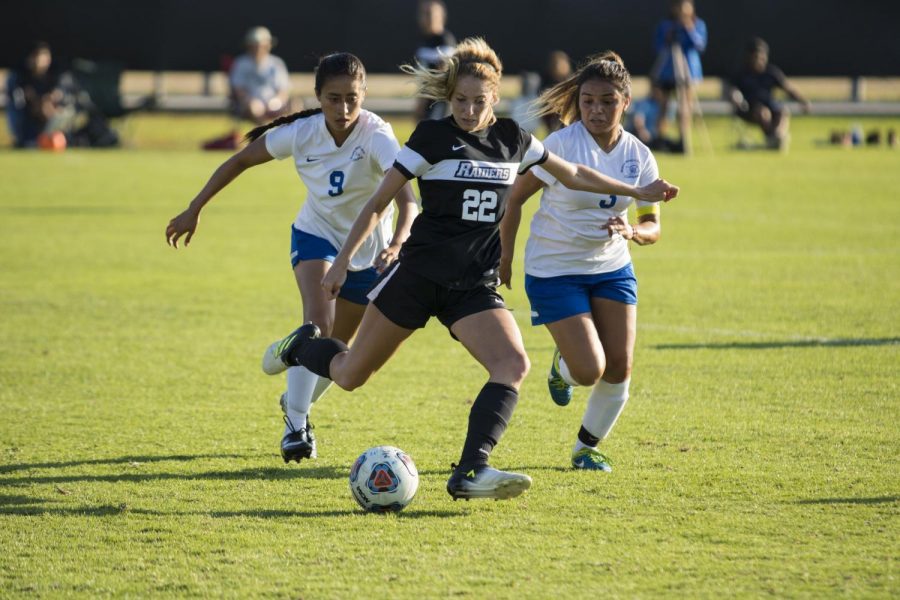 Defender, Taylor Johnson fends of two Santa Monica College forwards in the second half. Photo credit: Eric Caldwell