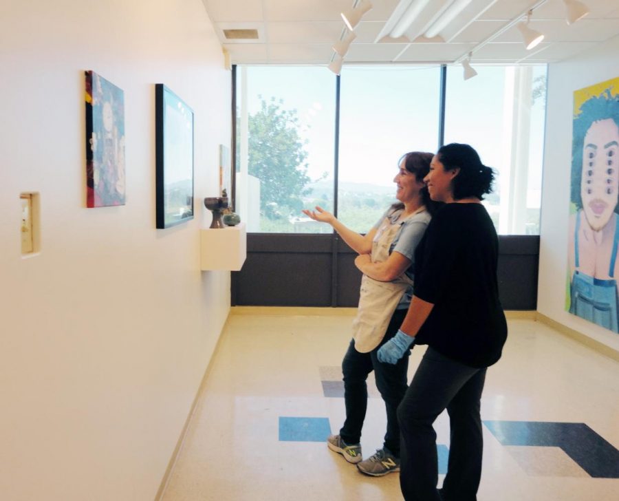 The New Student Art Gallery, just opened, and Moorpark College art majors, Leslie Stahle, center, and Yenelli Law, right, view the offerings. Photo credit: Lisette Davies Ward