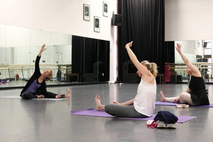 Tracy Stewart, middle, and Mary Pat Weber, right, imitate Sydney Sims pose at a free yoga class. The class is offered every Tuesday at noon. Photo credit: Danny Corrigan