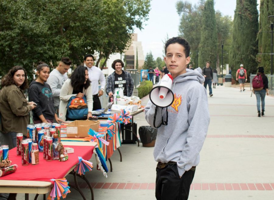Nick Salazar, 18, Business major uses a megaphone to draw people toward his clubs Day of the Dead event. La Raza club offered pan de muerto, or bread of the dead, and champurado, or Mexican hot chocolate. Photo credit: Martin Bilbao