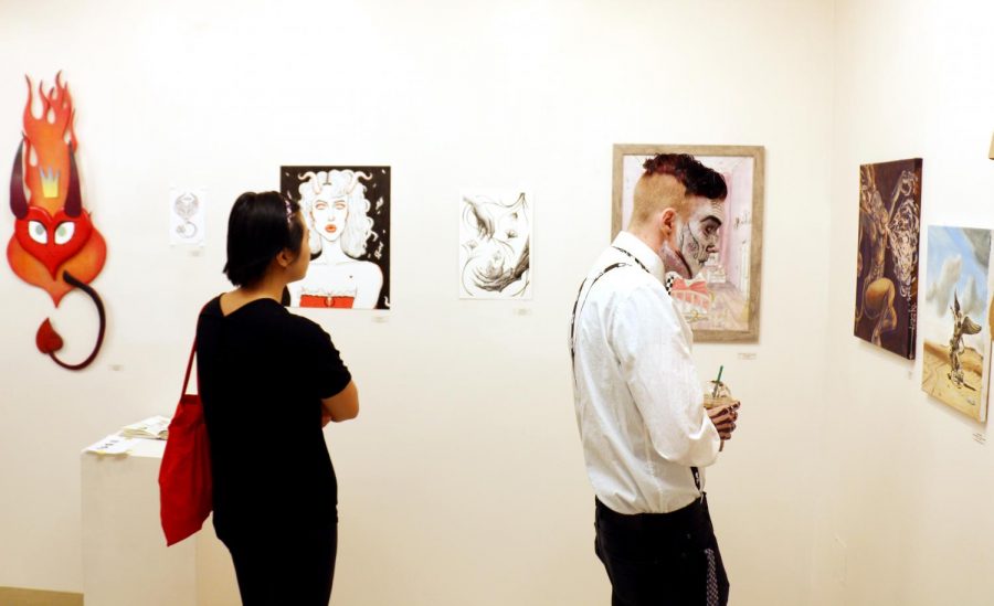 Jacob Waitkuweit, 19, right, takes a moment to observe the art hanging in the student art gallery. Mediums werent limited to paintings and illustrations, but also included sculpture and other mediums. Photo credit: Danny Corrigan