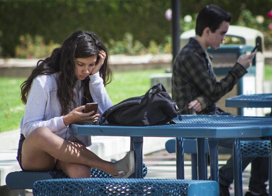 Ciera Northrup, 18, explores her social media, in the Moorpark College quad, as she waits for her next class, on April 12, 2018. Northrup, a sociology major, says she prefers face-to-face communication, but enjoys using Instagram and Snapchat. Photo credit: Evan Reinhardt
