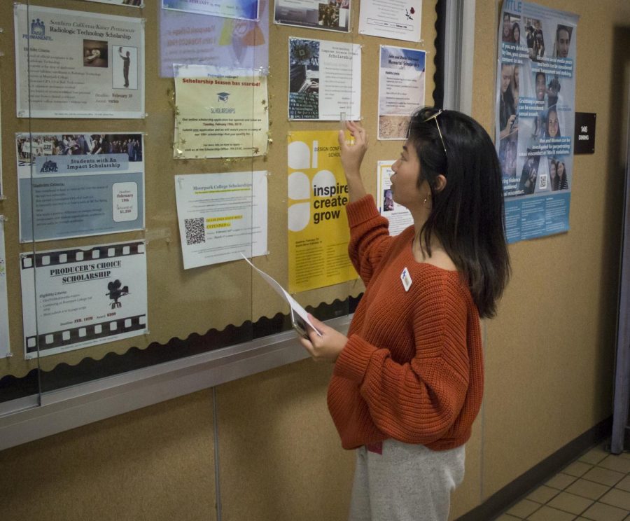 Mikyla Maglente, student worker for the Scholarship Office, updates the deadline for scholarship applications on the bulletin board next to the cafeteria, on Feb. 5, 2019. Photo credit: Evan Reinhardt