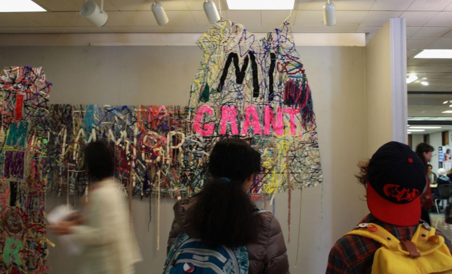 Students view the ceiling and wall-hanging art with the words migrant weaved atop a combination of fabrics and strings. Photo credit: Shariliz Poveda