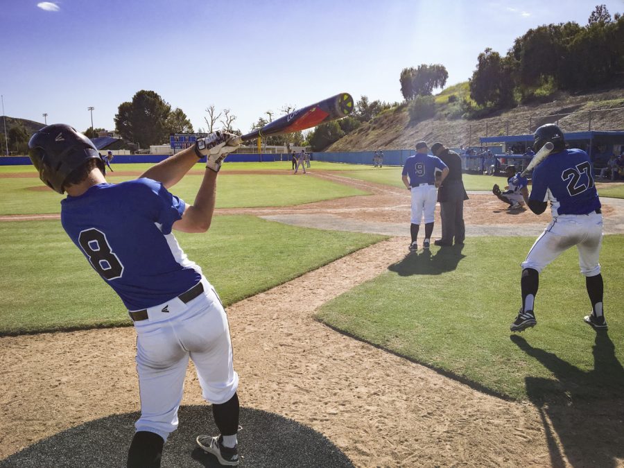 Moorpark infielders Cameron Kinsner, left, and Alex Vega, right, are taking a few practice swings in between half innings. Kinsner and Vega were held without a hit in their 4-2 loss on March 28, 2019. Photo credit: Ryan Ketcham