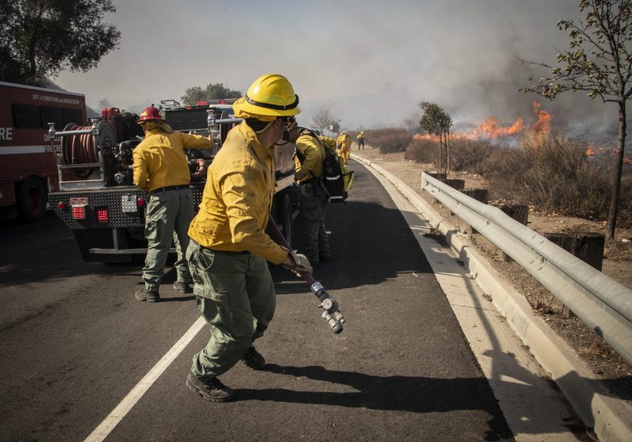 Firefighters unspool hose as the flames of the Easy Fire approach East Olsen Road in Simi Valley, Calif. on Wednesday, Oct. 30. Photo credit: Evan Reinhardt