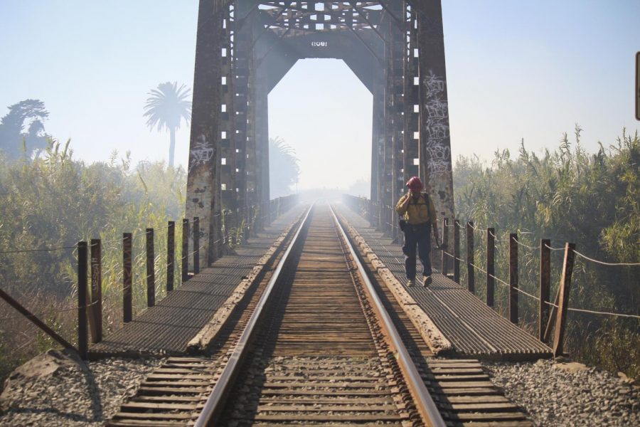 A firefighter crosses the Union Pacific Railroad bridge after clearing brush from a fire in Ventura, CA on Friday, Oct. 25, 2019.