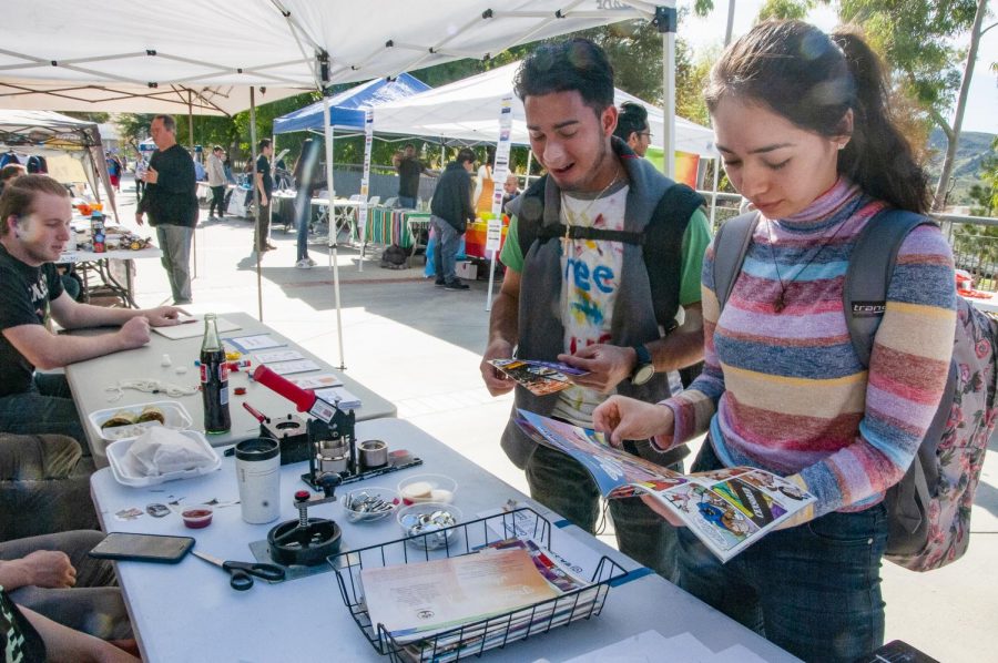 Carlos Hernandez, left, and Carmen Fregoso talk with representatives of the Moorpark College MakerSpace booth at Club Rush on Tuesday Jan. 28. Hernandez and Fregoso were making complimentary custom pins with materials set out by the club. Photo credit: Morgan Ellis