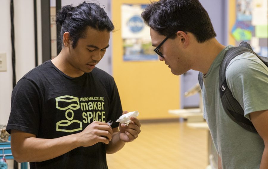 Ayrlron Arellano, MakerSpace staff member, cleans up a 3D printed model made by Kent Duke, right, on Monday, March 2, in the MakerSpace. Duke designed a 3D model and printed it for a business info systems class. Photo credit: Evan Reinhardt