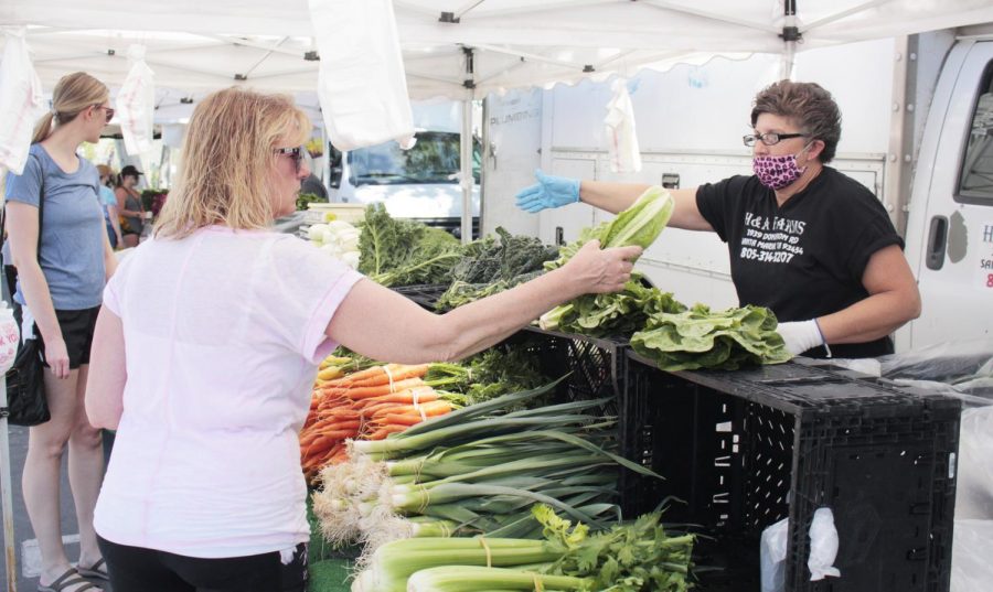 Georgina Bonfert from Simi Valley shops for produce at the Simi Valley Farmers Market on April 24, 2020. After the photo was taken Monce Macias at right, from Santa Maria gave Bonfert gloves to handle the food. Photo credit: Justin Downes