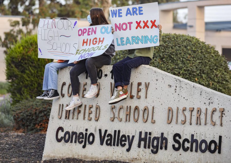 Protesters sit along the Conejo Unified School district sign during the Reopen Our Schools rally at Conejo Valley Unifieds district office in Thousand Oak, Calif. on Wednesday, Oct. 21. Photo credit: Ryan Bough