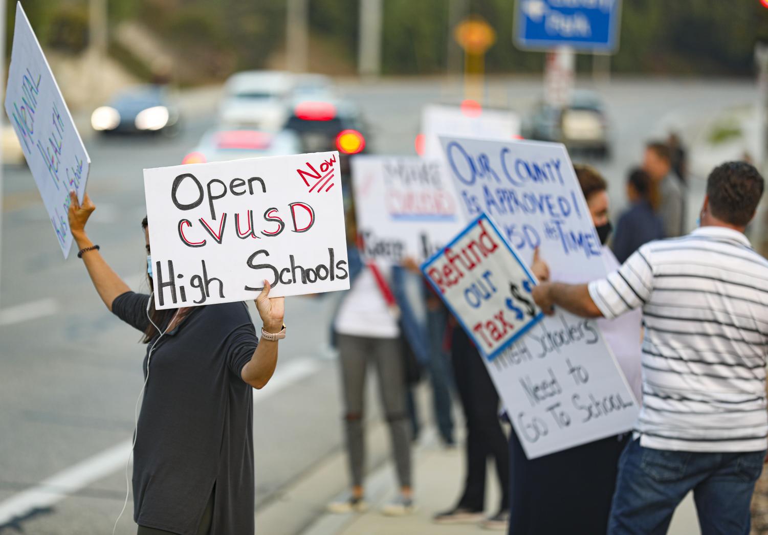 Protester hold up signs in front of the CVUSD district office during the