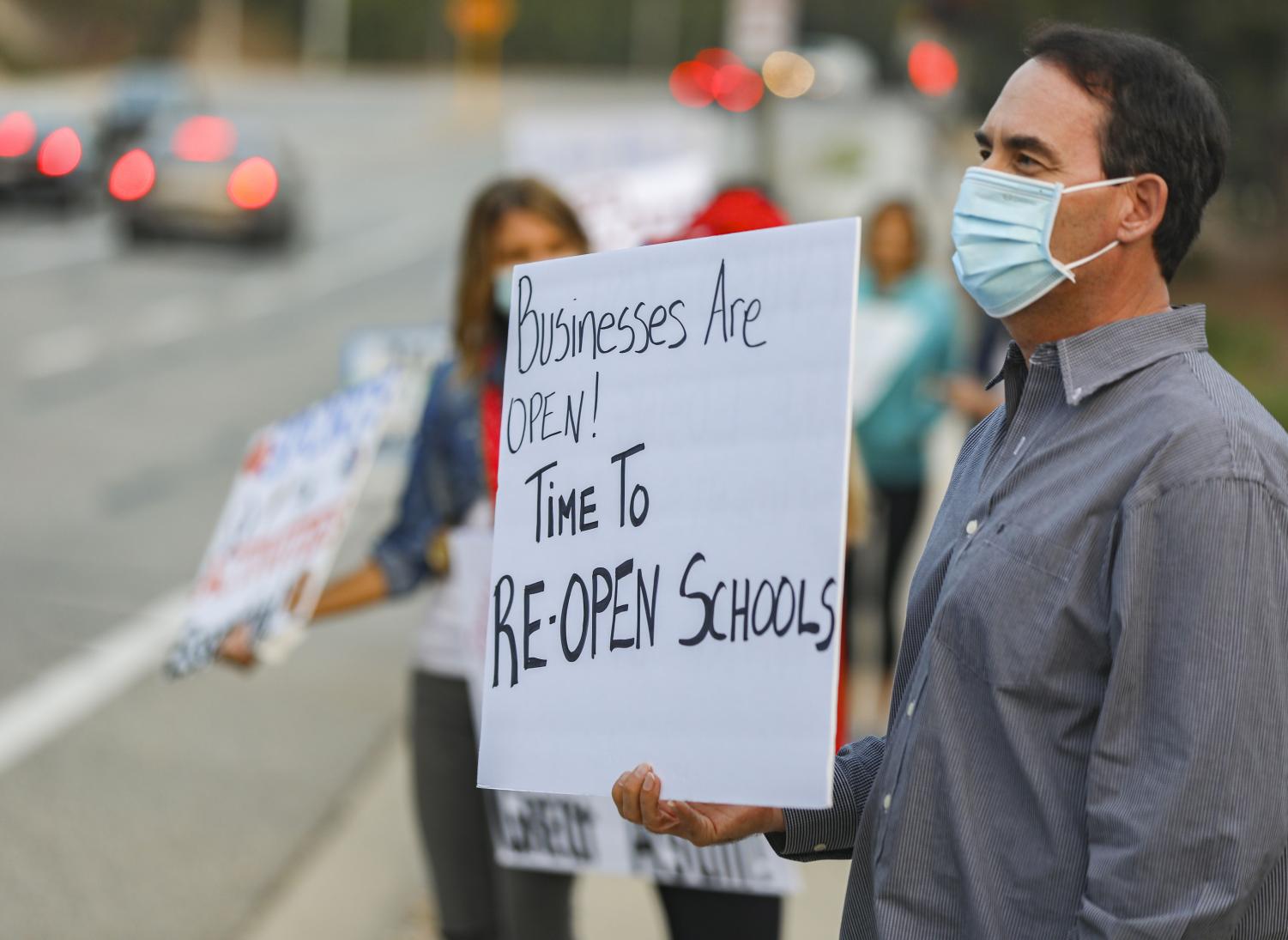 Raymond Fontayne holds up a sign in support of re-opening schools during the