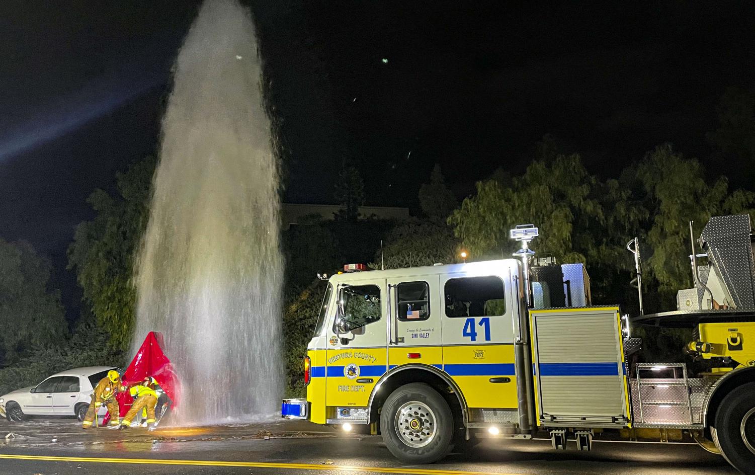 Firefighters struggle to shut off a fire hydrant due to freshly paved