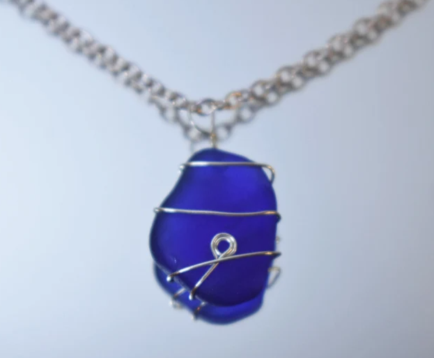 Hand wire wrapped blue glass found by Goldberg on a beach in Ventura repurposed into a necklace.