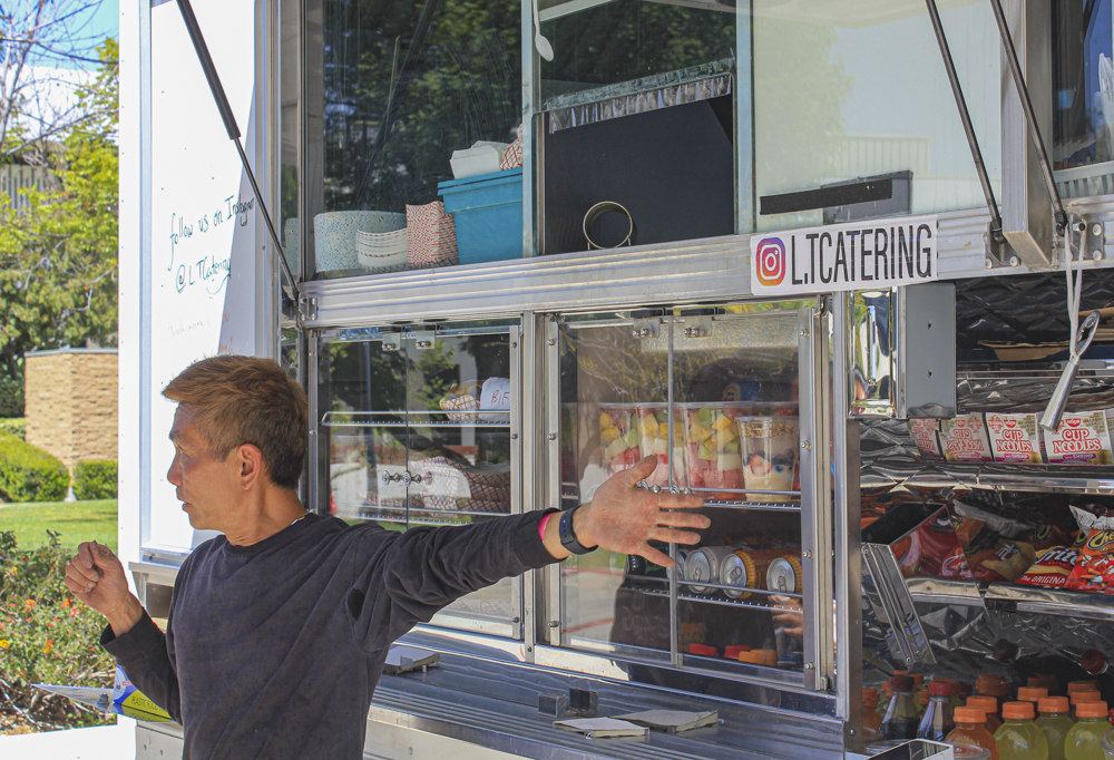 Peter Tshing shows different options of food, snacks and drinks that the L&T Catering food truck has to offer at Moorpark College on April 5, 2022.