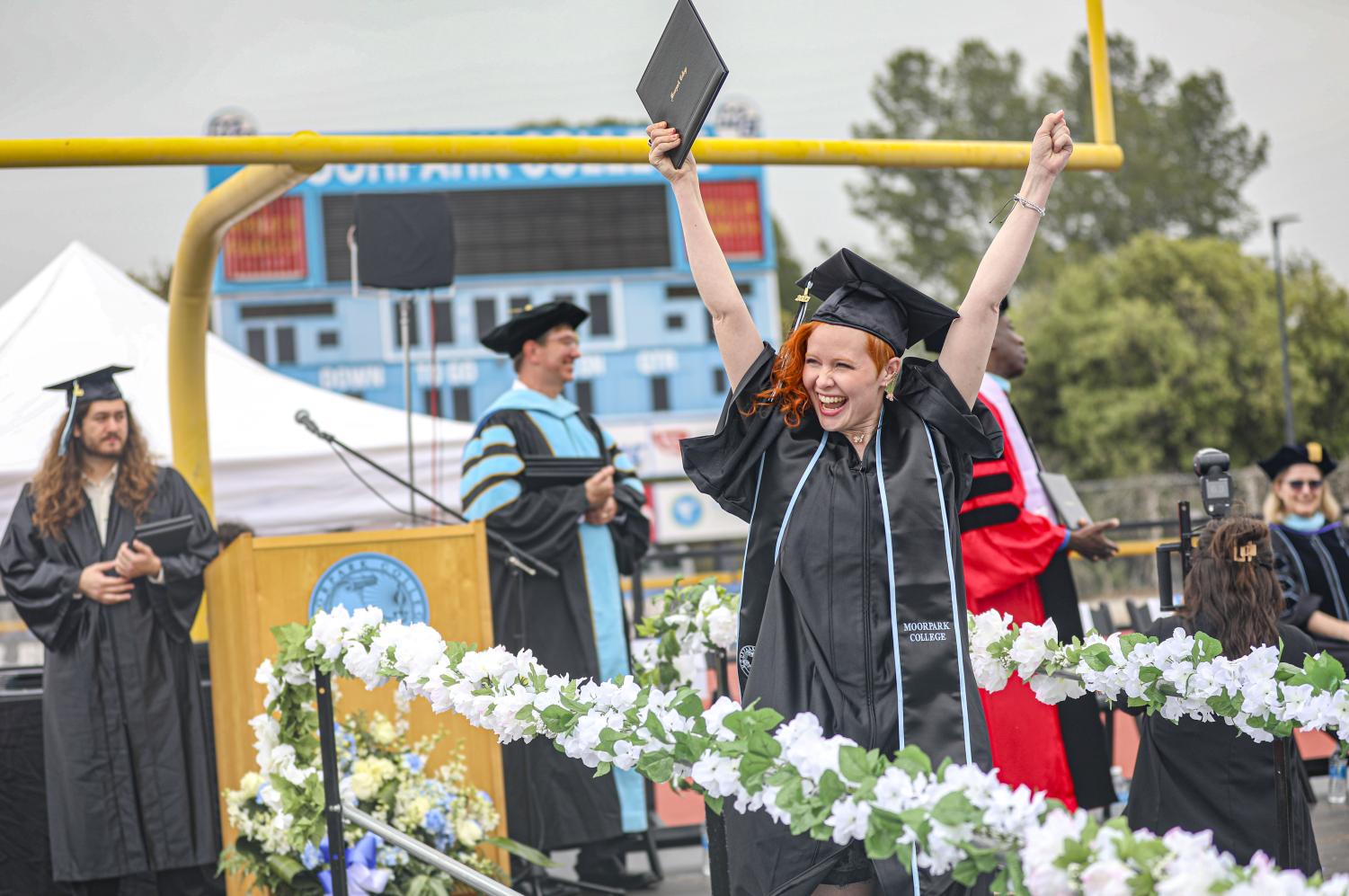 A 2023 graduate raises their arms in celebration after receiving their diploma on May 19, during Moorpark College's graduation ceremony in Moorpark, CA.