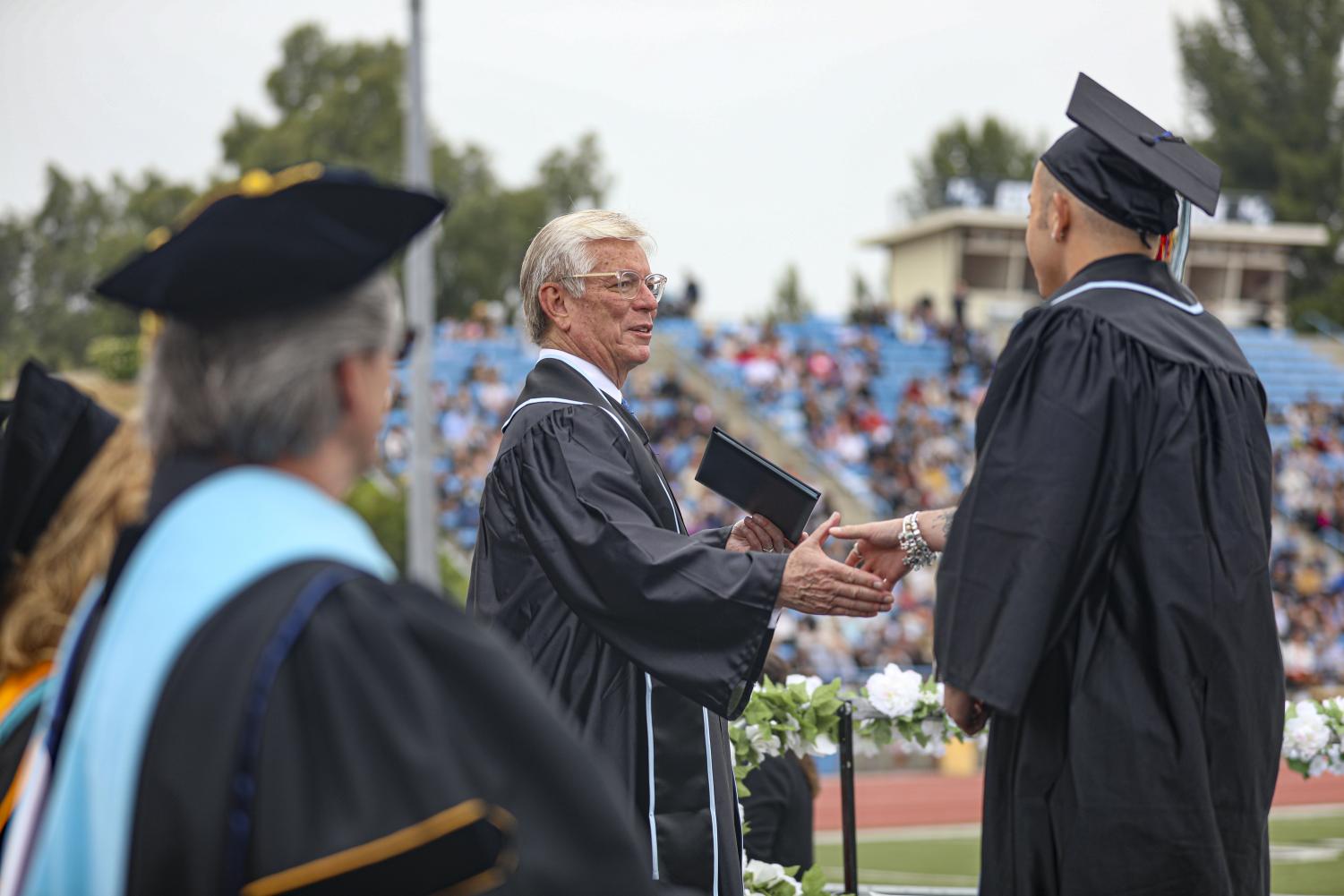 VCCCD Chair Bernardo Perez shakes hands with a graduating student on stage during the 2023 graduation ceremony on Friday, May 19, at Moorpark College.