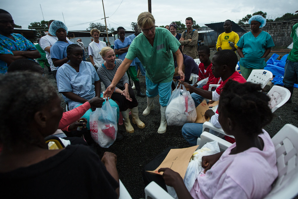 MSF members hand out care packages to survivors of the deadly ebola siege. Amidst the ebola epidemic that plagued much of Africa, MSF medical professionals helped provide care in communities that otherwise had limited access to medical assistance. Photo credit: Morgana Wingard on Flickr