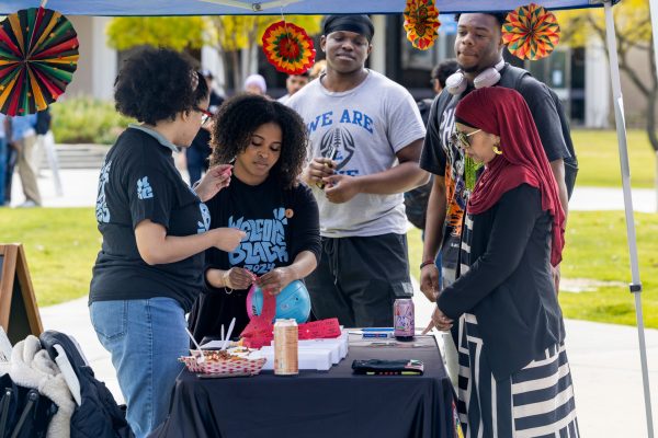 Black Student Union representatives gather around their information booth containing Black History Month items and tickets for food along the pathway of the quad on Tuesday, Feb. 4, 2025 in Moorpark, Calif. Photo credit: Heidi Martin