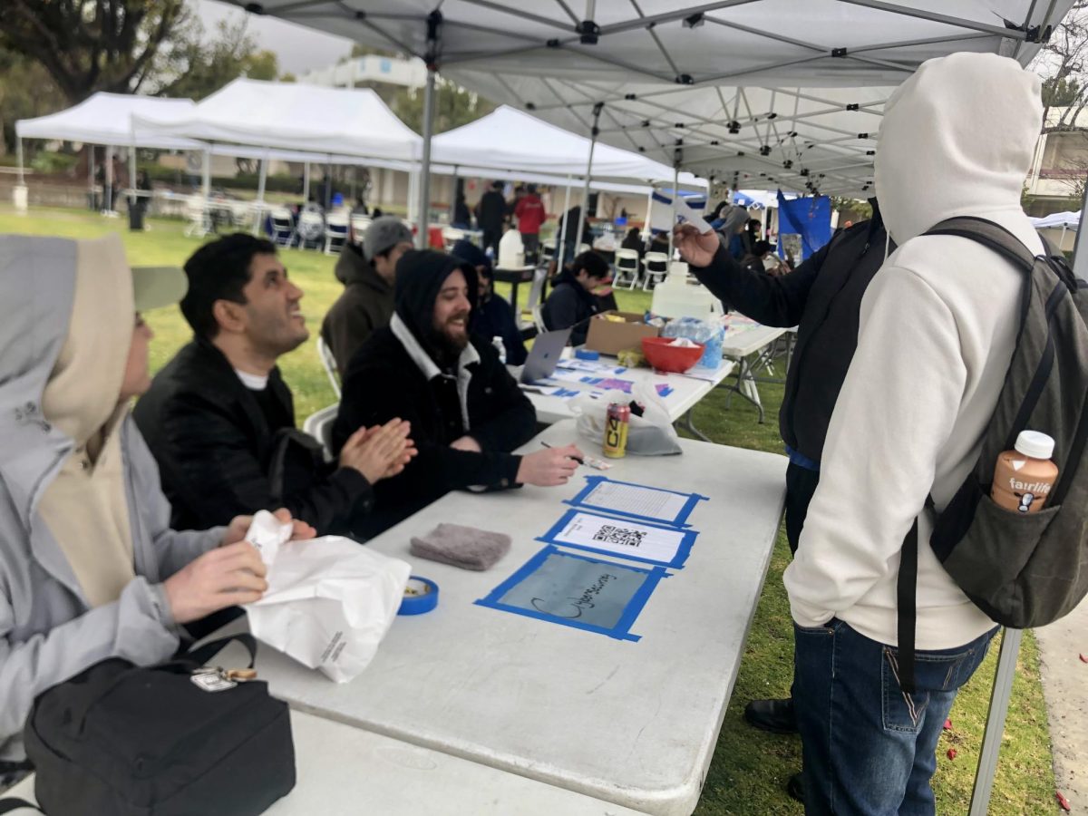 Cybersecurity Club vice president Joshua Kohantab (middle) and president Anthony Stumpf (right) greet prospective club members at the spring semester Club Rush event on Wednesday, Jan. 14, 2025 in Moorpark, Calif. Photo credit: Shane Douglas